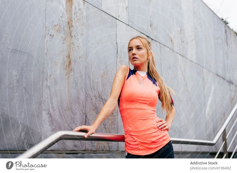Attraktive blonde Sportlerin ruht sich auf einer Treppe aus Mädchen Straße Großstadt laufen rennen Übung farbenfroh Gebäude attraktiv Sportbekleidung Athlet