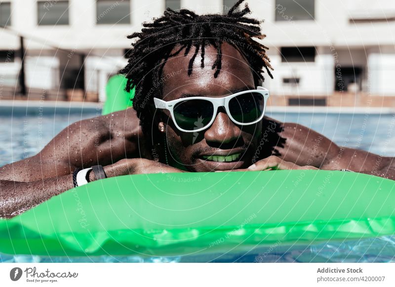 Schwarzer Mann mit Sonnenbrille im Schwimmbad aufblasbar Schlafmatratze Pool sich[Akk] entspannen sorgenfrei Sommer Urlaub genießen Lächeln männlich ethnisch