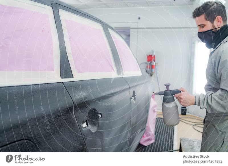 Mann mit Spritzpistole lackiert Auto in Werkstatt Farbe PKW Pistole Arbeiter Mundschutz Aerosol Spray Meister Automobil männlich Uniform Beruf Werkzeug