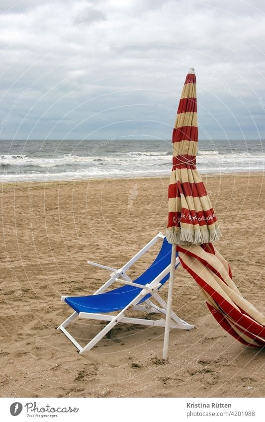 liegestuhl und sonnenschirm am strand von trouville gestreift geschlossen sandstrand leer einsam verlassen meer küste nebensaison nachsaison vorsaison