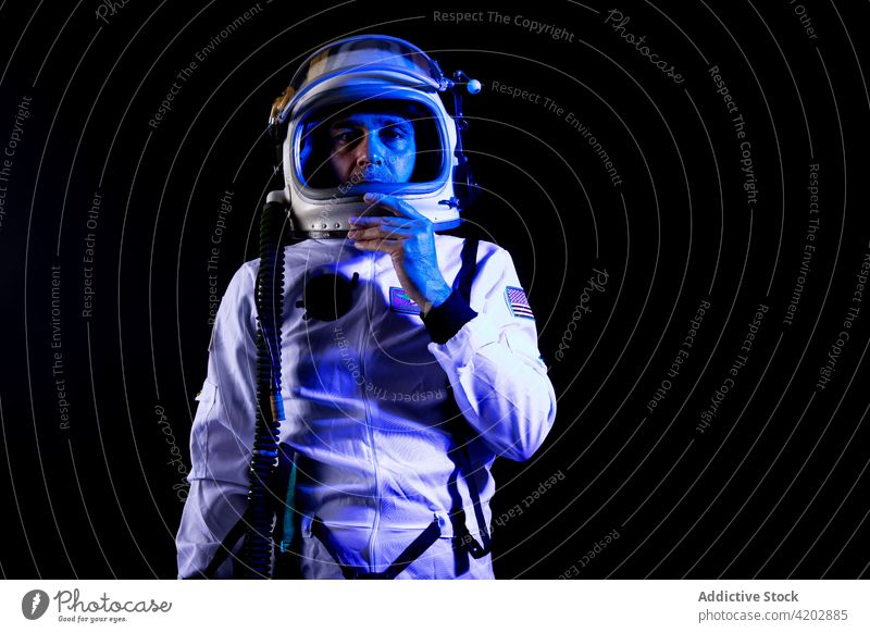 Astronaut im Raumanzug in blauem Neonlicht stehend Mann Schutzhelm professionell ernst Kosmonaut schützend Panzerung Raumfahrer Missionsstation neonfarbig Licht
