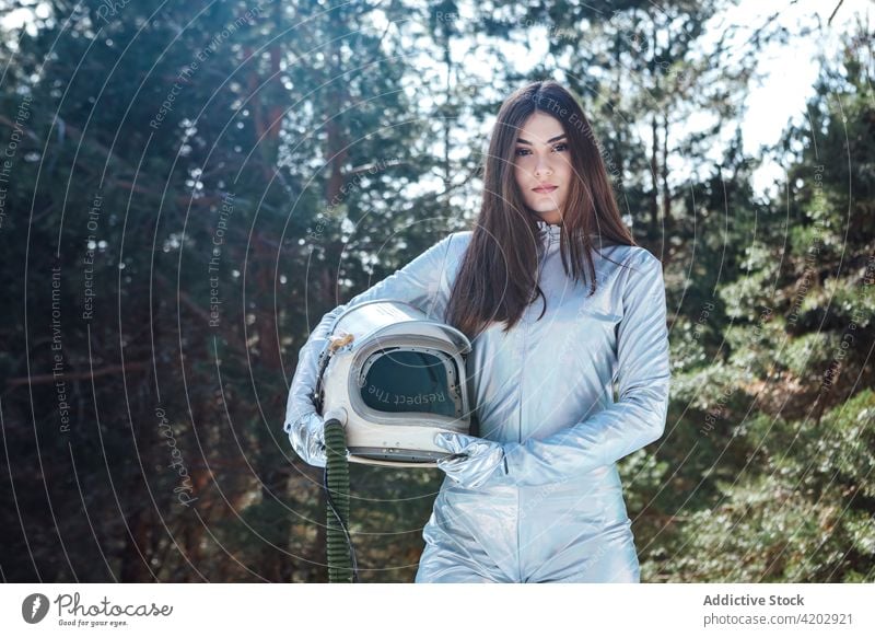 Attraktive Astronautin im verschneiten Wald stehend Frau Schnee Kosmonaut Raumanzug Windstille Winter Astronomie Schutzhelm Entdecker emotionslos professionell