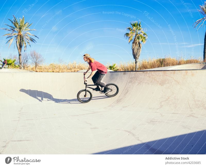 Sportler fährt Trialbike im Skatepark Biker Mitfahrgelegenheit Testversion Training aktiv Mann bmx Skateplatz Blauer Himmel wolkig tropisch exotisch Handfläche