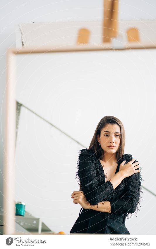 Wehmütige Frau, die sich in einem Spiegel auf einer Staffelei spiegelt Reflexion & Spiegelung wehmütig Kunst feminin sanft sensibel allein charmant Ohrringe