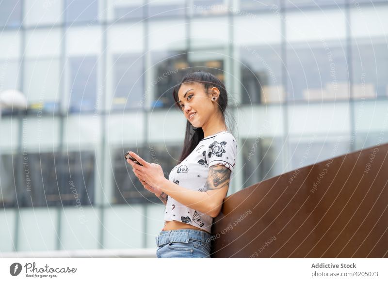 Asiatische Frau benutzt Smartphone auf der Straße Großstadt benutzend ruhen fettarm urban Stil modern ethnisch asiatisch jung Mobile Telefon Browsen Tattoo