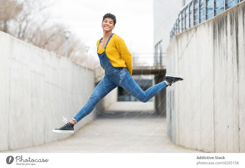 Unbekümmerte schwarze Frau springt in der Stadt über die Straße springen sorgenfrei Moment heiter Freiheit Sprung Großstadt Energie ethnisch Afroamerikaner