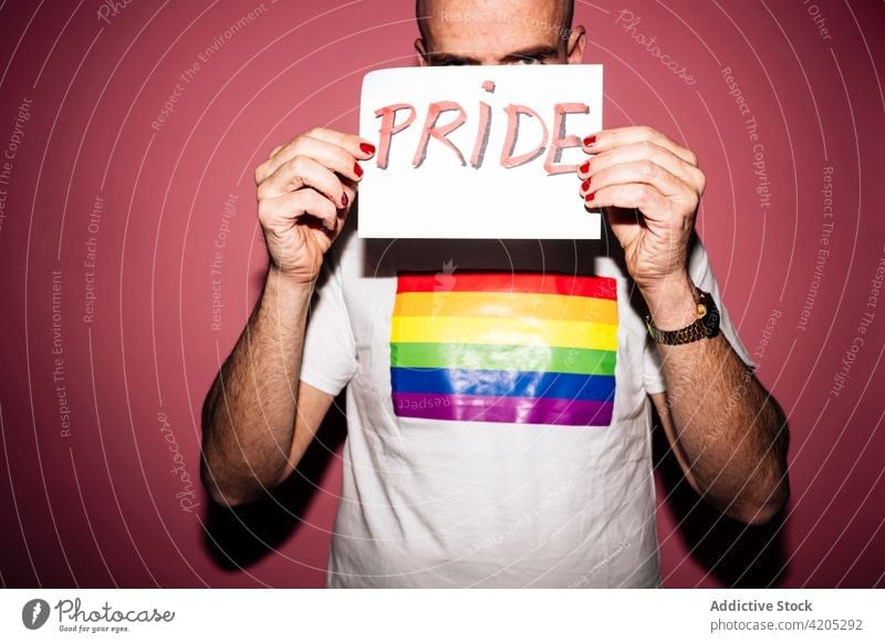 Positive Homosexuell zeigt Papier mit Pride Inschrift in rosa Studio Mann Homosexualität Stolz LGBTIQ schwul queer lgbt Grimasse Deckblatt Tierhaut Konzept
