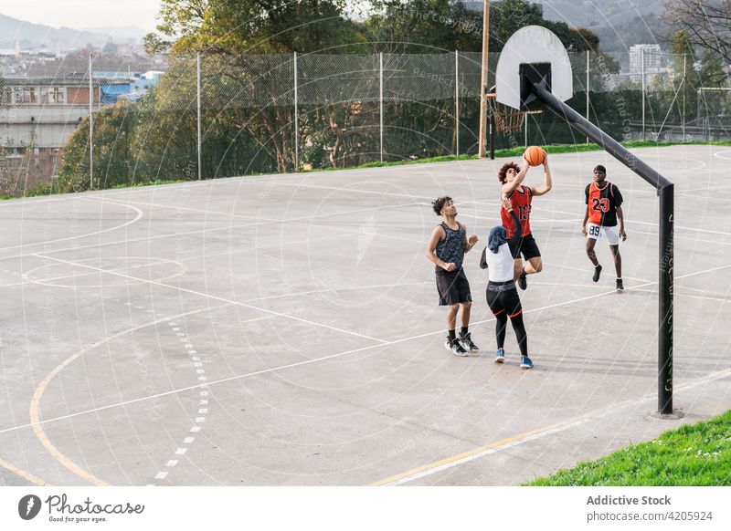 Unterschiedliche Menschen spielen Basketball auf dem Platz Streetball Spieler Zusammensein Team Ball Straße Sportpark rassenübergreifend multiethnisch