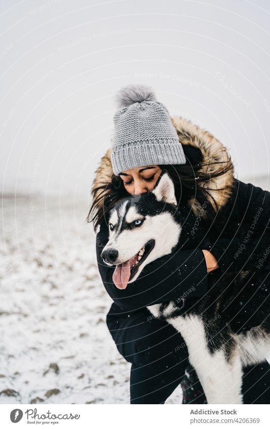 Weibchen in Umarmung mit Husky auf Winterwiese Frau Feld Haustier Spaziergang Besitzer Streicheln Landschaft Hund Wiese gehorsam Schnee tagsüber warme Kleidung