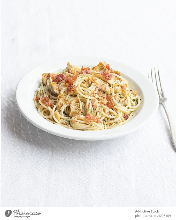 Nahaufnahme eines Tellers mit Spaghetti und Artischocken von oben gesehen Lebensmittel frisch Tomate Käse Paprika Schinken Gemüse Spätzle Prosciutto Vegetarier