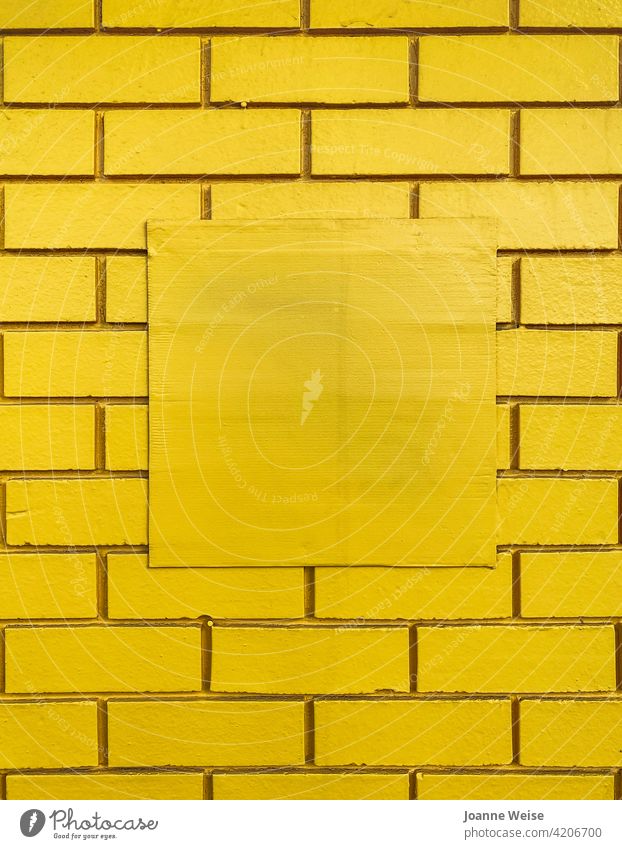 Gelbe Ziegelwand mit zentraler quadratischer Freifläche. gelb gelber Hintergrund Backsteinwand Wand gelbe Wand Textfreiraum Mitte Farbfoto Baustein