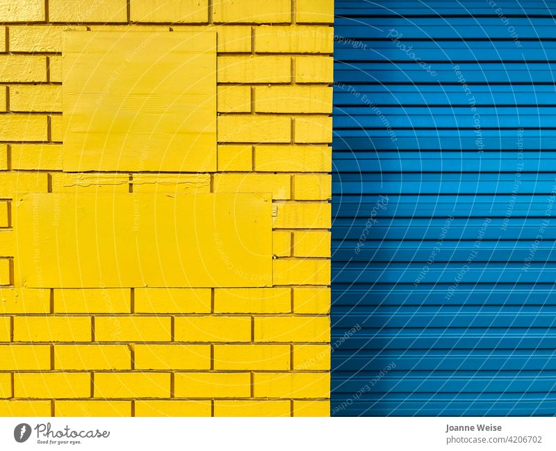 Gelbe Ziegelwand und blaues Rolltor. blau und gelb gelbe Wand blaue Tür Farbfoto Außenaufnahme Tag Metall Architektur Gebäude Eingang Bauwerk