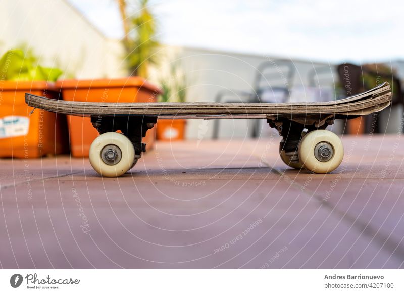 Blick auf ein altes Skateboard auf der Terrasse des Hauses. Selektiver Fokus Skateboarding extrem Beton Surfen Rad Ansicht Freizeit Seite Farbe hoch Genuss