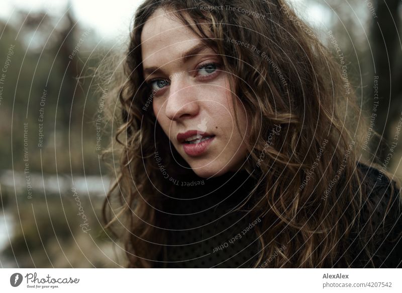 Portrait einer jungen Frau mit langem, brünettem, lockigem Haar vor einer Moorlandschaft junge Frau 18-30 Jahre schön Schönheit Haare lange Haare Locken