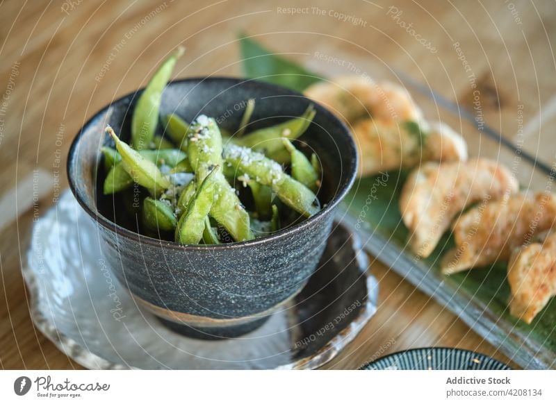 Sushi-Teller und Sojabohnen-Snack Edamames frisch lecker grün Amuse-Gueule Gemüse Veganer Bohne Orientalisch Salz Draufsicht Mahlzeit Restaurant gyozas