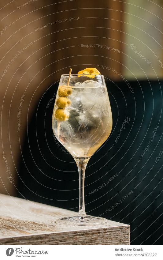 Ein Glas Cocktail mit Oliven Weinglas Martini Getränk Alkohol Tonic trinken Tisch Saum oliv Eis Schnaps hölzern Raum Kristalle Erfrischung Würfel durchsichtig