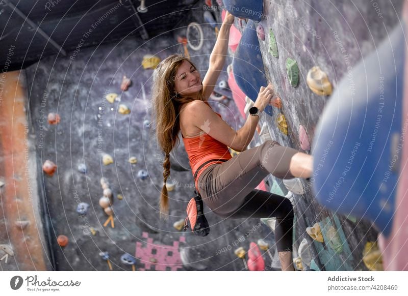 Aktive Frau klettert an der Wand im Fitnessstudio Sportlerin klettern Bouldern Fokus extrem Konzentration Stärke Training stark Bergsteiger aktiv sportlich