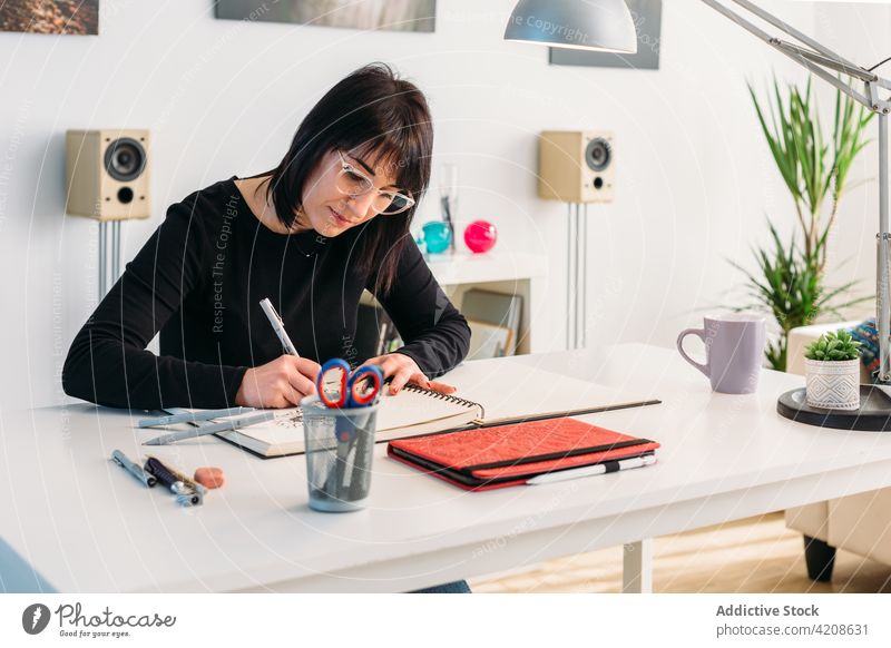 Kreative Frau zeichnet in Skizzenbuch zu Hause zeichnen Künstler Notizblock Zeichnung heimwärts kreativ Talent Kunst Tisch Raum sitzen Hobby Vorstellungskraft