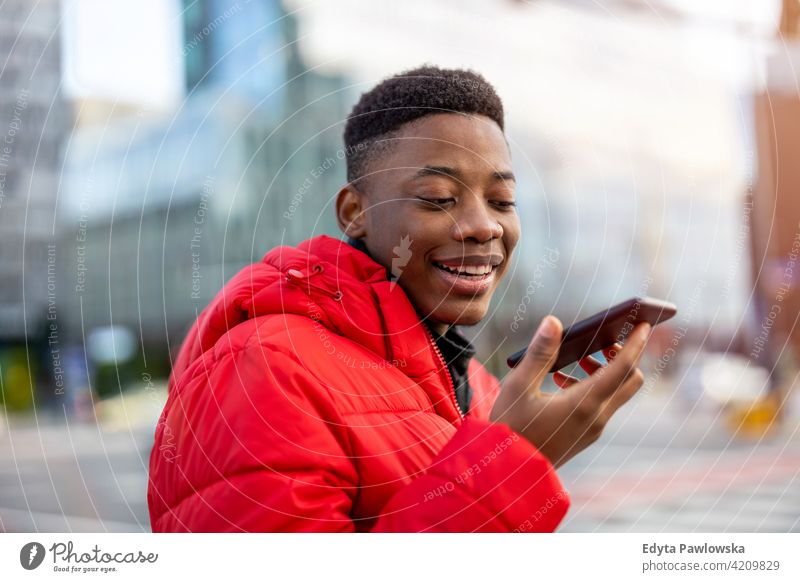 Junger Mann mit Smartphone im Freien in städtischer Umgebung schwarz außerhalb Straße urban tausendjährig Stehen Afrikanisch Großstadt Warschau eine