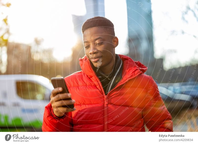 Junger Mann mit Smartphone im Freien in städtischer Umgebung schwarz außerhalb Straße urban tausendjährig Stehen Afrikanisch Großstadt Warschau eine