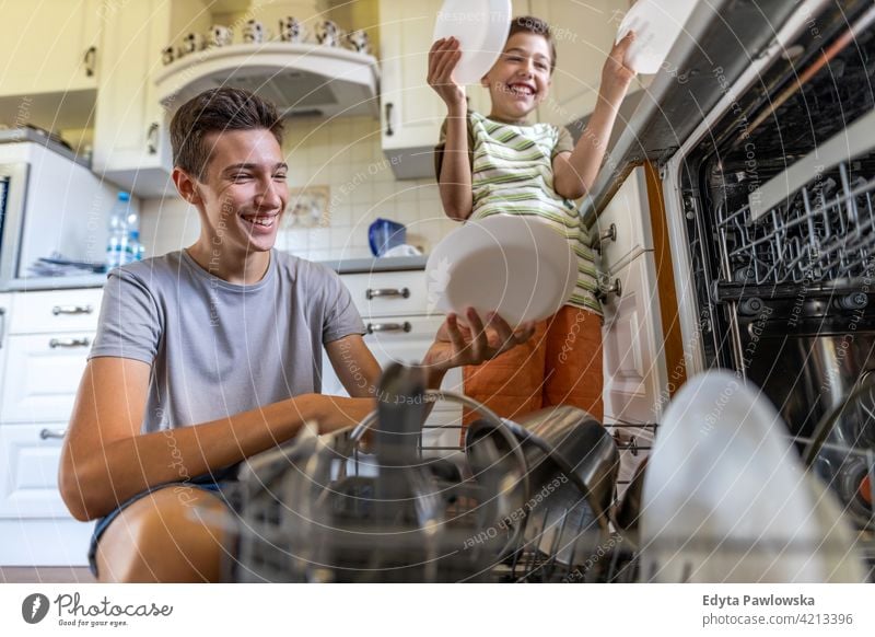 Zwei Jungen beladen gemeinsam den Geschirrspüler zu Hause Geschirrspülen Wäsche waschen Speise Beladung Maschine Hausarbeit Hausarbeiten Küche Hilfe Lernen