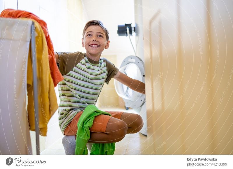 Junge lädt Waschmaschine zu Hause Wäscherei Beladung Kleidung Bad Hausarbeit Hausarbeiten Hilfe Lernen Familie Menschen Kind Sohn Kinder Lifestyle elementar
