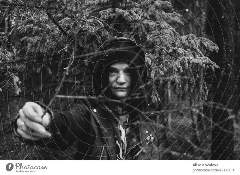 Mädchen hält einen Ast im Wald Porträt Frau Gesicht einen Zweig haltend Niederlassungen schwarz auf weiß in einem Wald Hut Lederjacke Finger Arme Halt zeigend