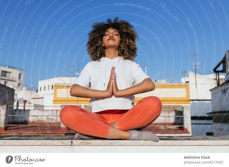 Schwarze Frau sitzt in Lotus-Pose und meditiert während einer Yogastunde meditieren Lektion online Laptop padmasana üben ruhig ethnisch schwarz Afroamerikaner