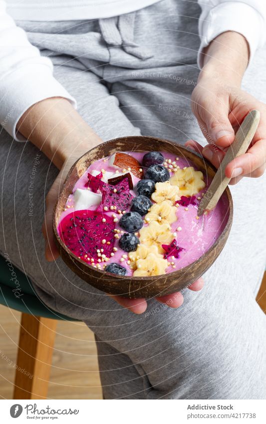 Crop-Frau mit leckerer Frühstücksschüssel voller Früchte Kraftschale gesunde Ernährung Smoothie Frucht Nährstoff Vitamin exotisch reif Beine gekreuzt