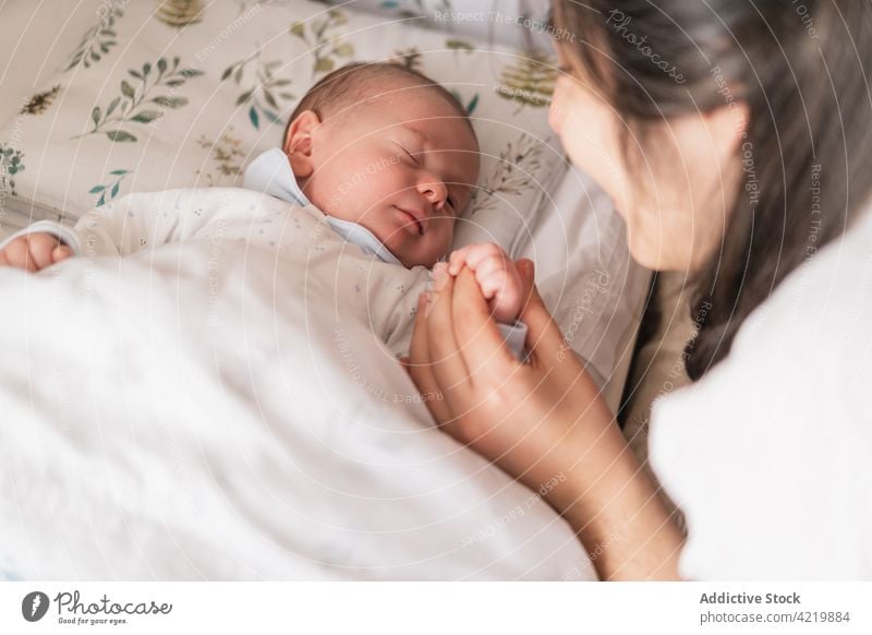 Ein Elternteil hält sein neugeborenes Baby im Bett an der Hand Händchenhalten schlafen Säuglingsalter unschuldig Windstille Harmonie idyllisch Mittagsschlaf