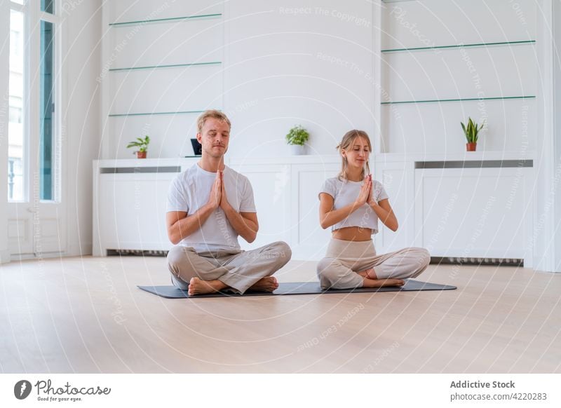 Ruhiges Paar meditiert gemeinsam auf einer Matte zu Hause meditieren Zusammensein Yoga Lotus-Pose Zen Windstille Gebetshände Harmonie üben Augen geschlossen