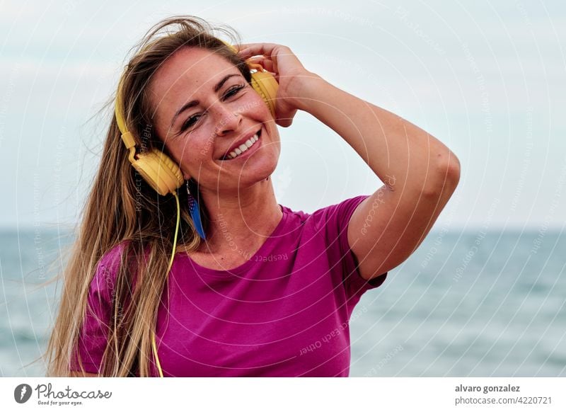 Junge Frau am Strand hört Musik mit gelben Kopfhörern Sommer schön Meer Natur Mädchen jung MEER Hut Erholung Lifestyle im Freien eine Menschen Himmel hören