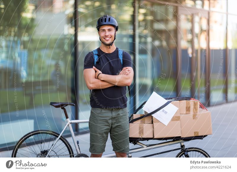 Fahrradkurier, der eine Lieferung auf einem Lastenfahrrad macht Menschen junger Erwachsener Mann männlich Lächeln Glück blauer Kragen Kurier Meldereiter