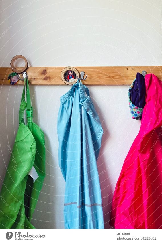 Kindergartengarderobe Garderobe Kindheit Haken aufhängen Kleidung magenta pink hellblau grün Regenhose Regenjacke Garderobenleiste Kleiderhaken Bekleidung