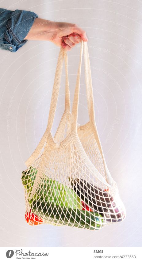 Die Hand einer Frau hält einen Stoffbeutel voller Obst und Gemüse. Plastikfrei. Müllfrei Tasche Bambus Biografie abbaubar kaufen farbenfroh Konzept Baumwolle