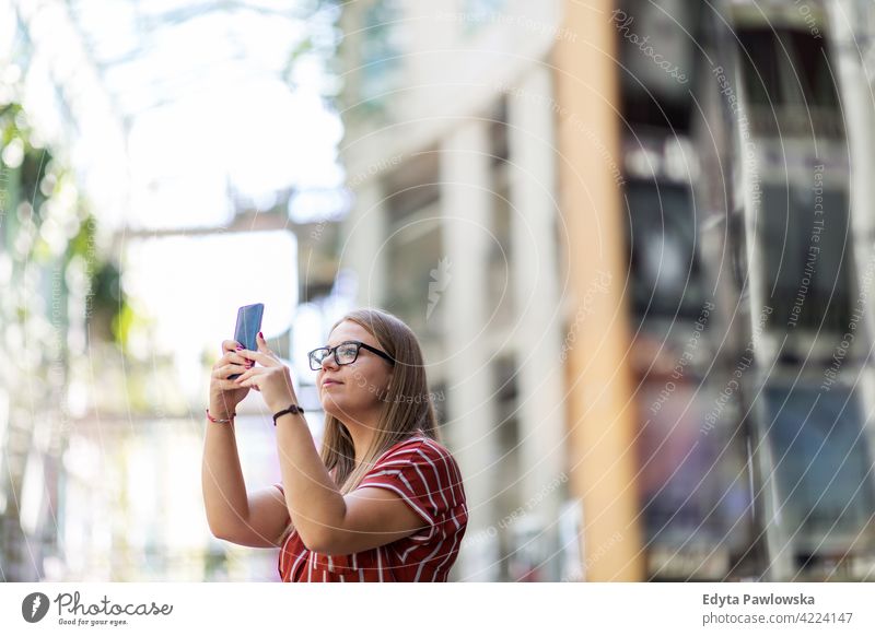 Junge Frau beim Fotografieren mit ihrem Smartphone körperpositiv Übergewicht Übergrößenmodell urban Großstadt aktiv Menschen junger Erwachsener lässig attraktiv