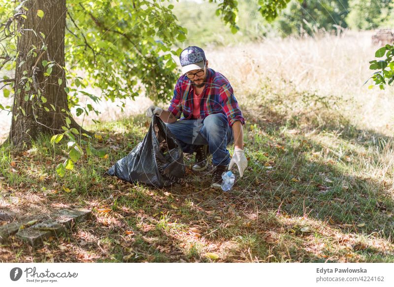 Junger Mann beim Aufsammeln von Müll in seinem örtlichen Park laufen wandern Wald Gras natürlich Landschaft Umwelt Baum außerhalb männlich Person Tag im Freien