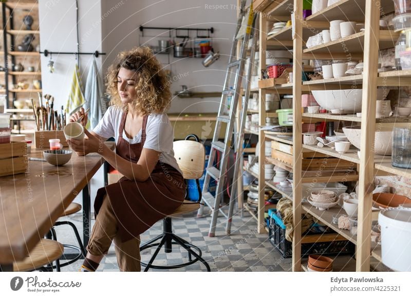 Kunsthandwerkerin bemalt eine Schale aus Ton im Kunstatelier Töpferwaren Künstler Keramik Arbeit arbeiten Menschen Frau jung Erwachsener lässig attraktiv Glück