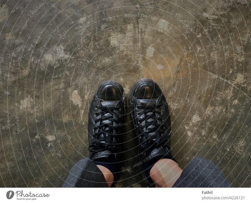 Schwarze Schuhe im Cafe auf dem grauen Boden. schwarz Café Stock Hintergrund Fuß Schuhbänder