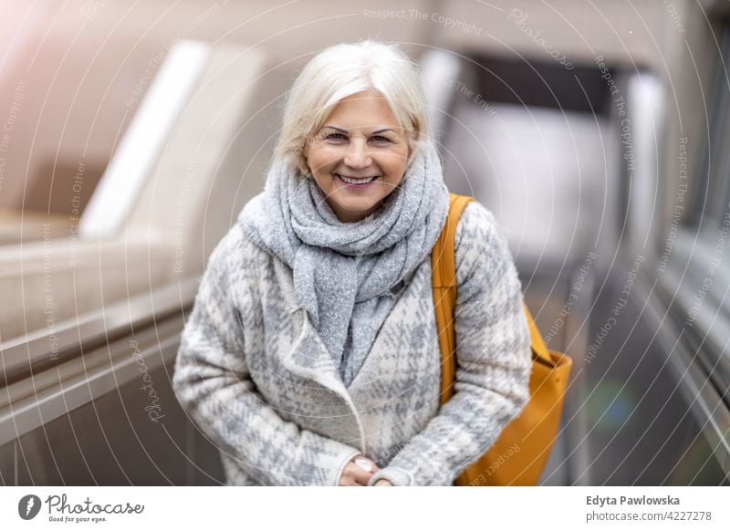 Glückliche Seniorin auf Rolltreppe Brille Lächeln genießend entspannt Positivität selbstbewusst natürlich Senioren Rentnerin Rentnerinnen Frau lässig im Freien