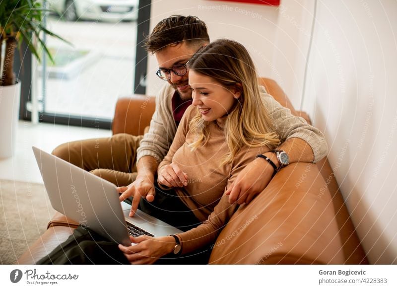 Junges Paar mit Laptop zusammen, während auf dem Sofa zu Hause sitzen Erwachsener Appartement attraktiv Freund sorgenfrei Kaukasier bequem Computer Liege Tag