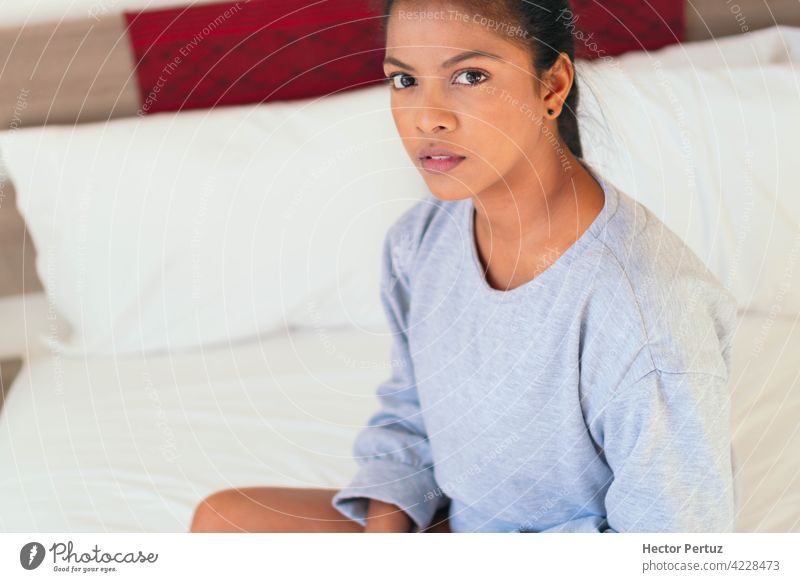 Eine attraktive junge Frau sitzt auf ihrem Schlafzimmerbett. Sie schaut in die Kamera schwarz Afrikanisch Glück Porträt Erholung Bett Menschen Schönheit Frauen