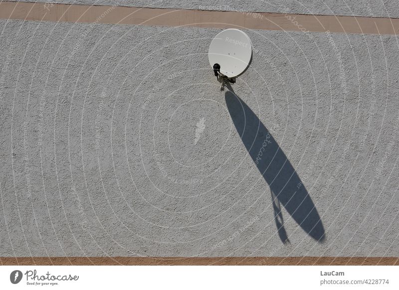 Kleine Satellitenschüssel mit großem Schattenspiel Fassade Hausfassade Sonne Sonnenlicht Schattenwurf klein Kommunikation Television Empfang empfangsbereit