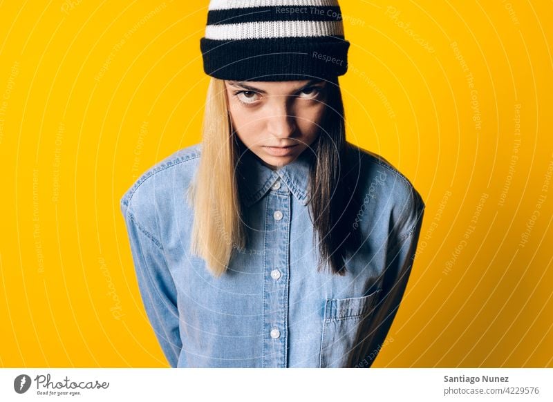Serious Girl Wearing Hat Portrait Atelier gelber Hintergrund Porträt in die Kamera schauen Ausdruck farbenfroh Frisur lässig jung Mädchen Frau ernst