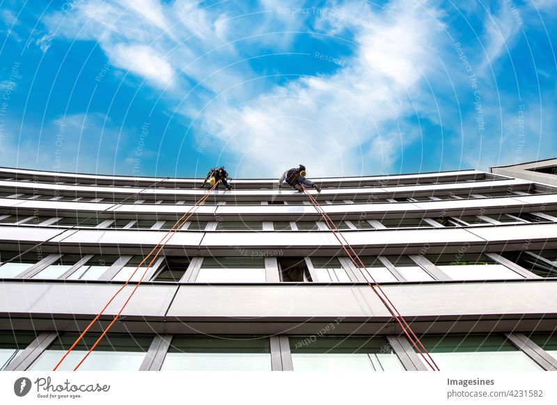 Fensterputzer! Zwei männliche industrielle Kletterer putzen Fenster an einem Gebäude. hoch in der Luft gegen blauen Wolkenhimmel hoch oben Himmel Erwachsener