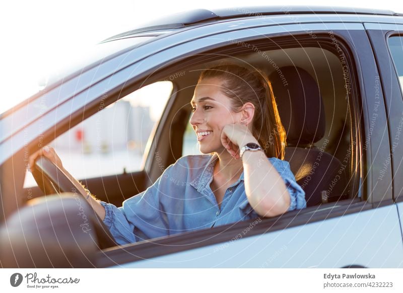 Glückliche Frau, die ein Auto fährt und lächelt Carsharing selbstbewusst Lächeln Befriedigung attraktiv schön junger Erwachsener Freude positiv Inhalt Sitzen