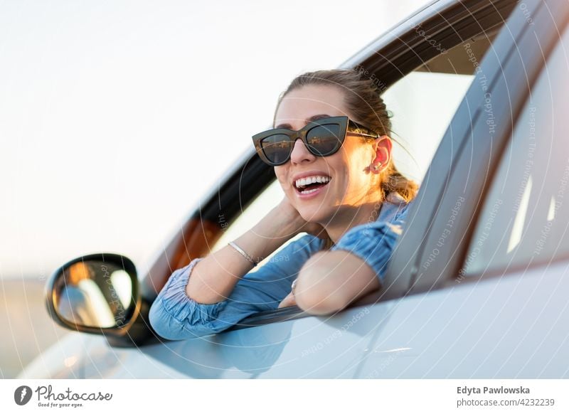 Glückliche Frau mit Sonnenbrille in einem Auto Carsharing selbstbewusst Lächeln Befriedigung attraktiv schön junger Erwachsener Freude positiv Inhalt Sitzen