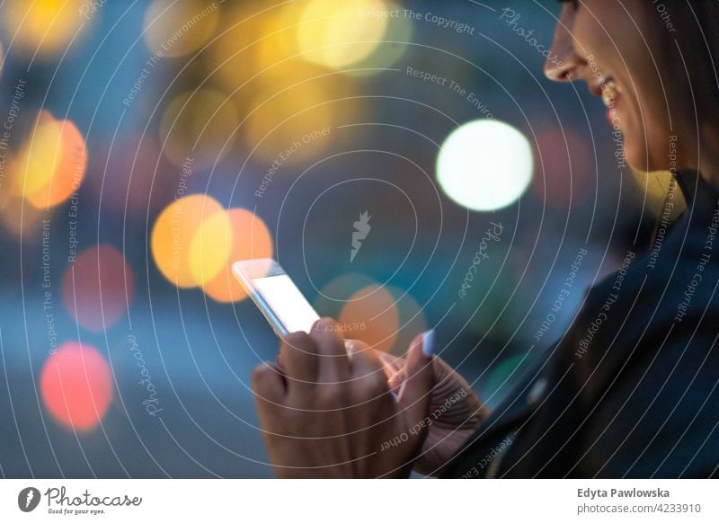 Junge Frau mit Smartphone bei Nacht in einer städtischen Umgebung urban Straße Großstadt aktiv Menschen junger Erwachsener lässig attraktiv Glück Kaukasier