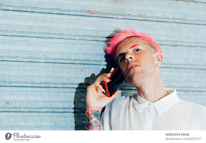 Stilvolle Homosexuell sprechen auf Smartphone auf blauem Hintergrund schwul Mode Tattoo cool Individualität Porträt benutzend Apparatur Gerät Mann Piercing