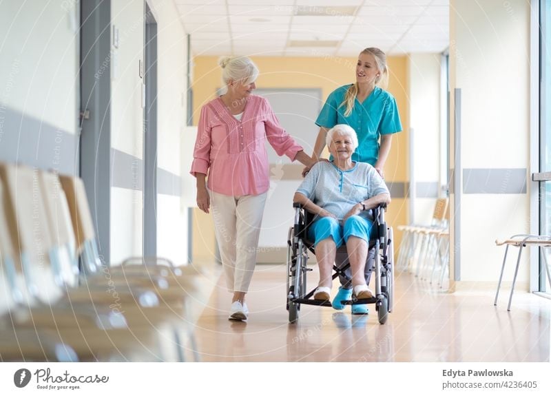 Ältere Frau im Rollstuhl mit ihrer Tochter und Krankenschwester rollstuhl Behinderung körperliche Beeinträchtigung Behinderte Mobilität abstützen Zugänglichkeit
